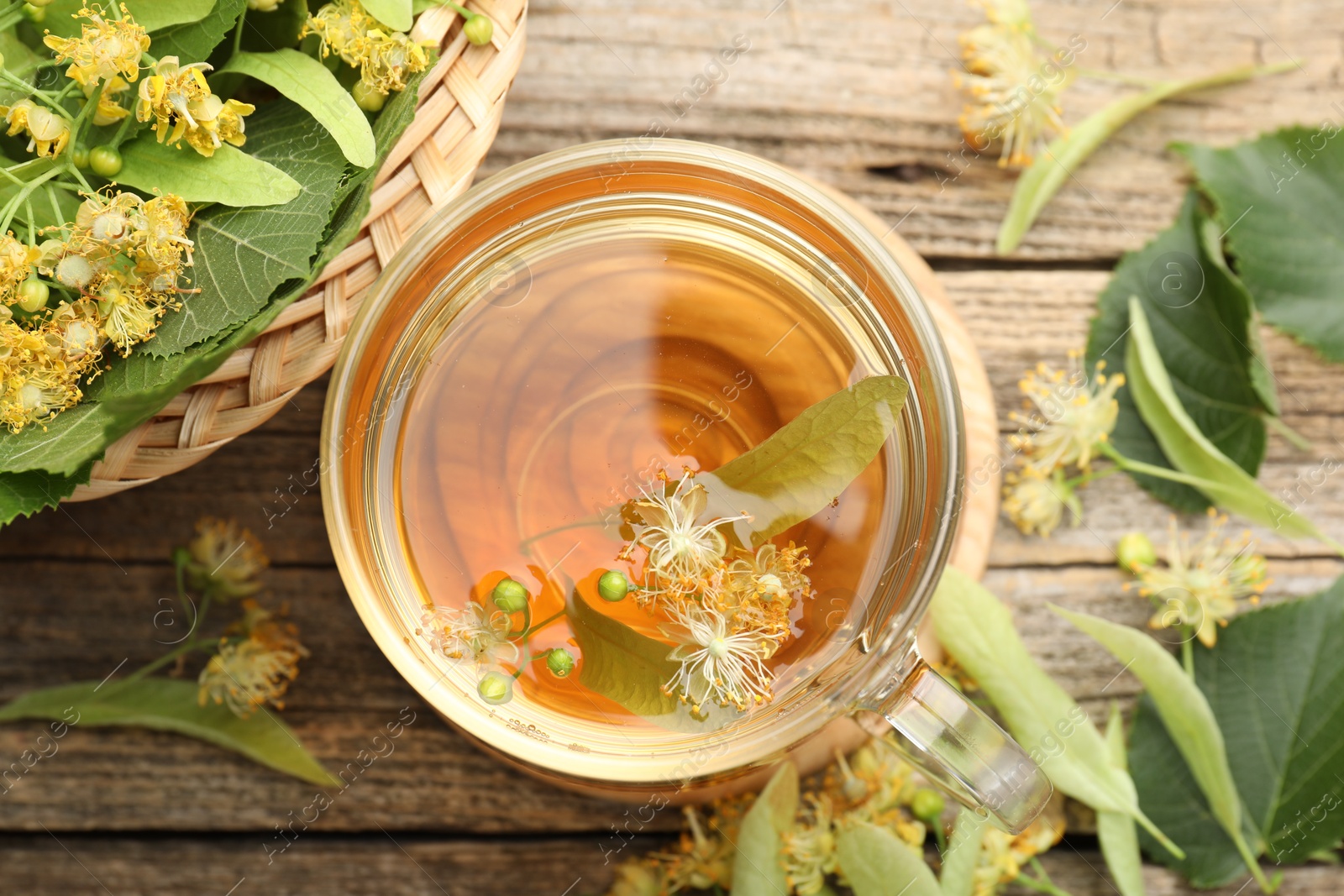 Tasty linden tea in cup, leaves and flowers on wooden table, flat lay Photo of Tasty linden tea in cup, leaves and flowers on wooden table, flat lay