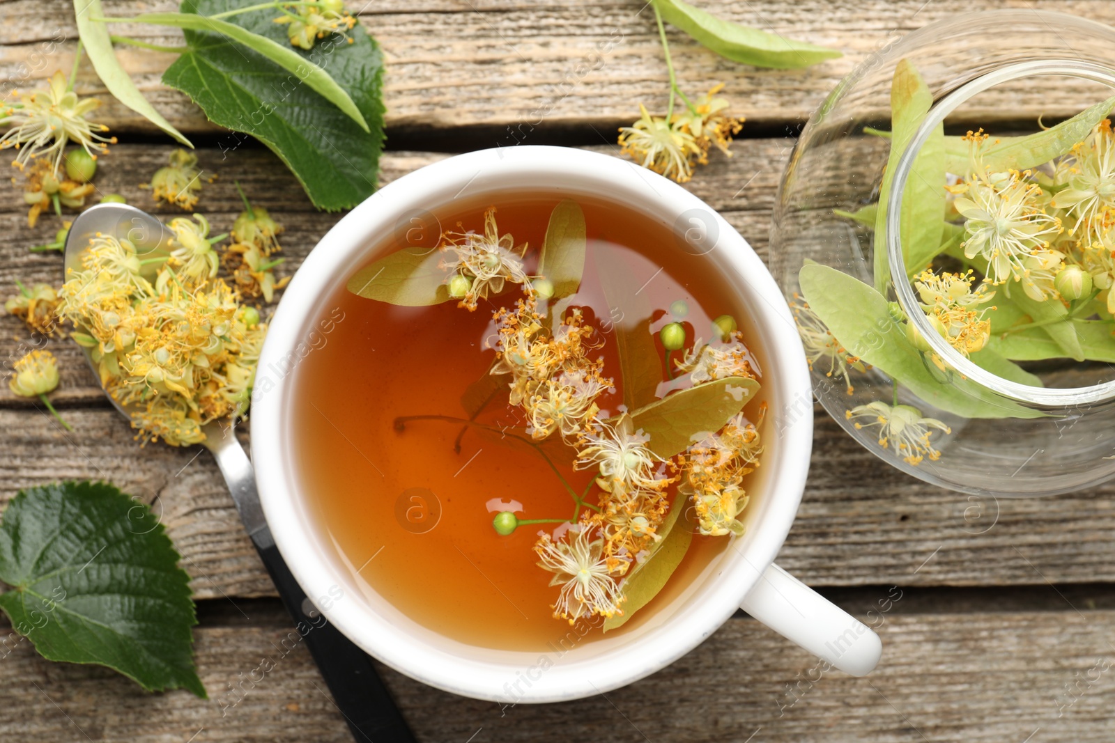 Tasty linden tea in cup, leaves and flowers on wooden table, flat lay Photo of Tasty linden tea in cup, leaves and flowers on wooden table, flat lay