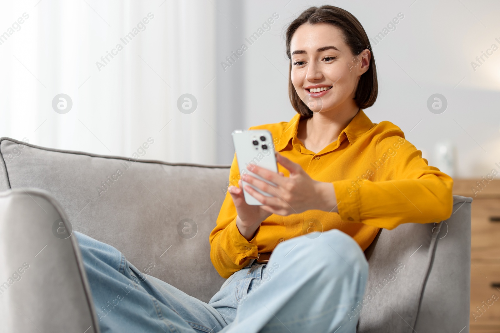 Woman using modern smartphone in armchair at home. Space for text Photo of Woman using modern smartphone in armchair at home. Space for text
