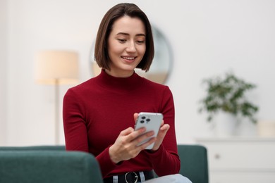 Photo of Woman using modern smartphone on sofa at home