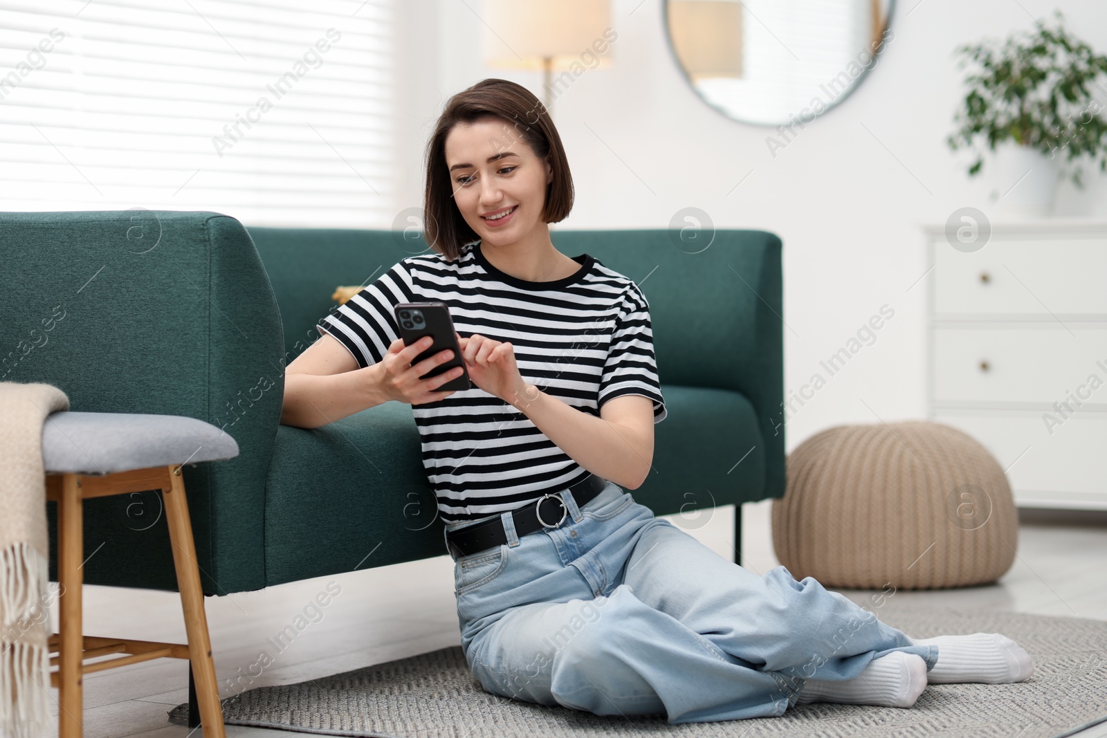 Woman using modern smartphone on floor at home Photo of Woman using modern smartphone on floor at home