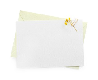 Photo of Blank invitation card and envelope with flower isolated on white, top view. Space for design