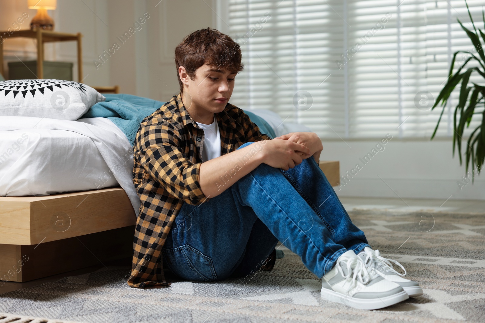 Teen problems. Upset teenage boy on floor at home Photo of Teen problems. Upset teenage boy on floor at home