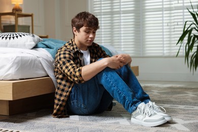 Photo of Teen problems. Upset teenage boy on floor at home