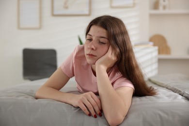 Photo of Upset teenage girl on bed at home