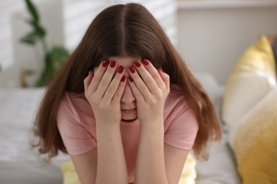 Photo of Upset teenage girl on bed at home