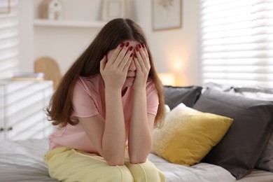 Photo of Upset teenage girl on bed at home