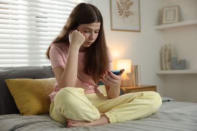 Photo of Upset teenage girl on bed at home
