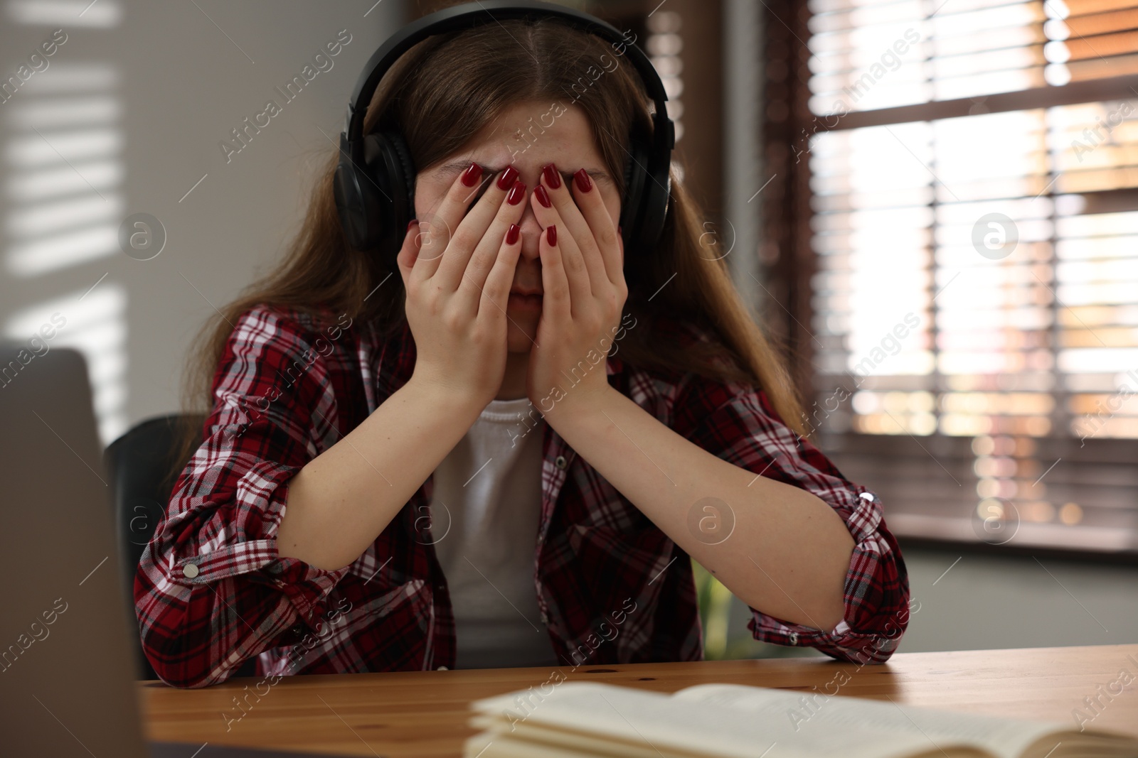 Stressed teenage girl studying at desk indoors Photo of Stressed teenage girl studying at desk indoors