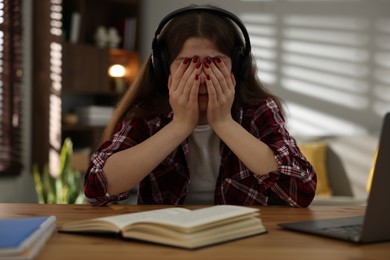 Photo of Stressed teenage girl studying at desk indoors
