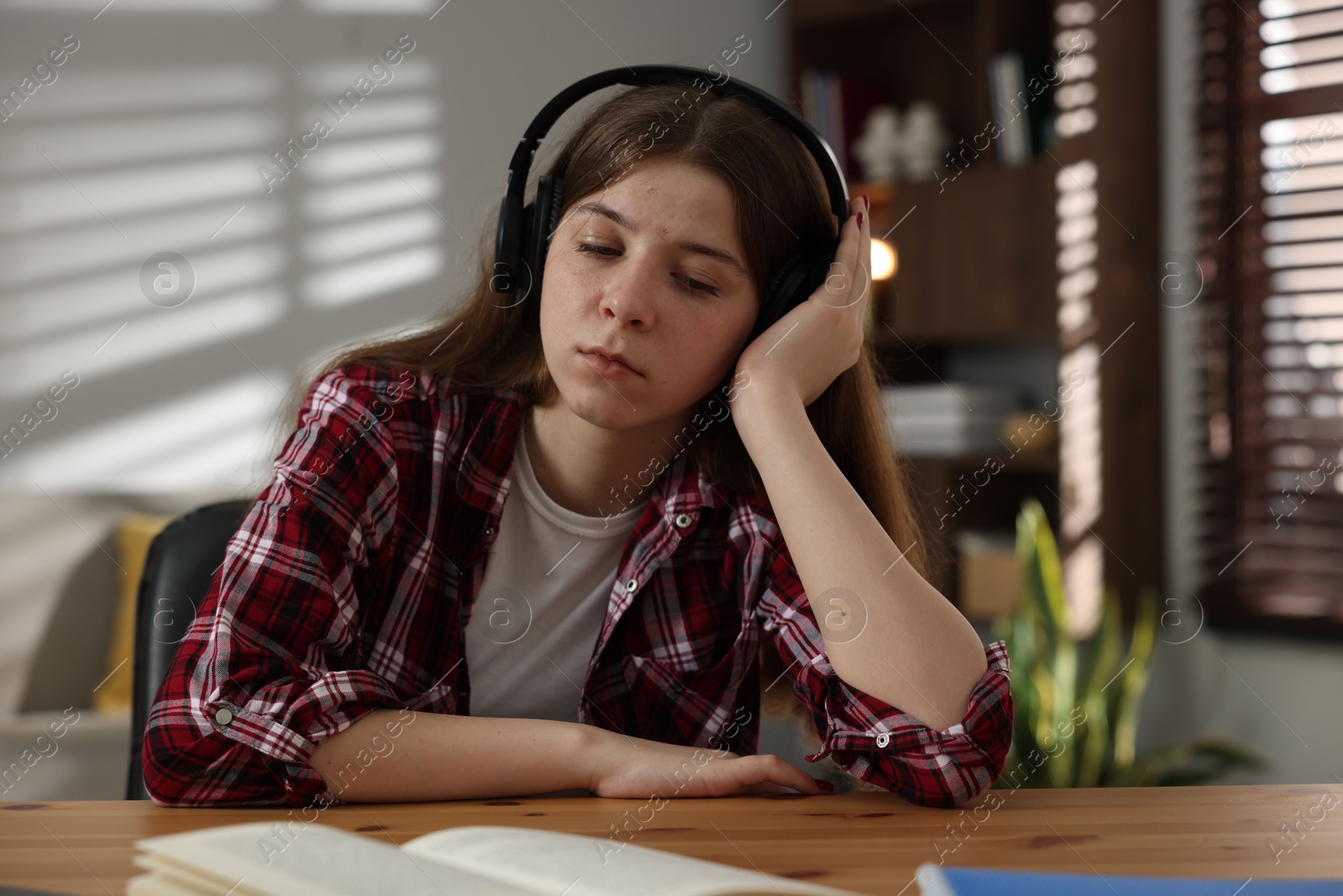 Stressed teenage girl studying at desk indoors Photo of Stressed teenage girl studying at desk indoors
