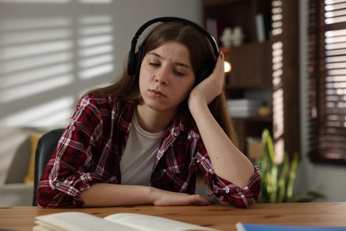 Photo of Stressed teenage girl studying at desk indoors
