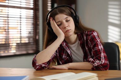 Photo of Stressed teenage girl studying at desk indoors