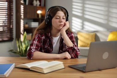 Photo of Stressed teenage girl studying at desk indoors