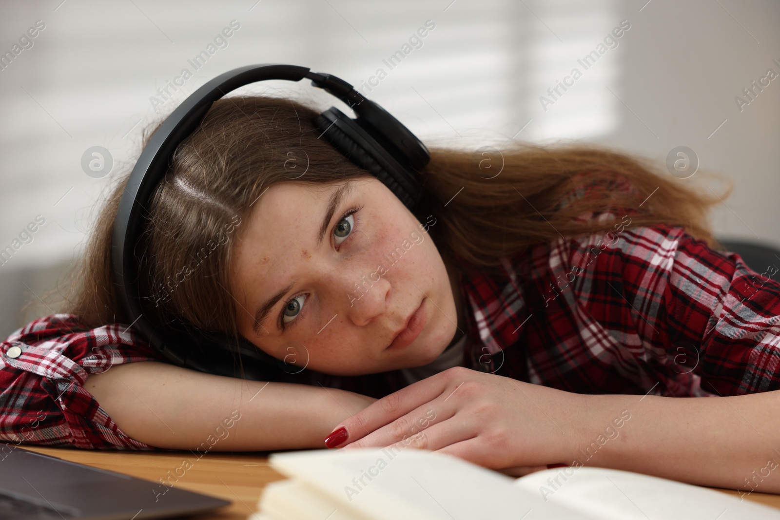 Stressed teenage girl studying at desk indoors Photo of Stressed teenage girl studying at desk indoors