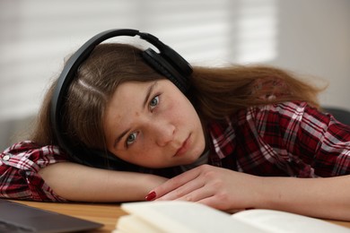 Photo of Stressed teenage girl studying at desk indoors