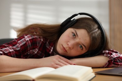 Photo of Stressed teenage girl studying at desk indoors