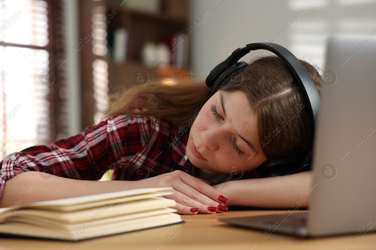 Stressed teenage girl studying at desk indoors Photo of Stressed teenage girl studying at desk indoors