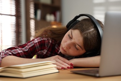 Photo of Stressed teenage girl studying at desk indoors