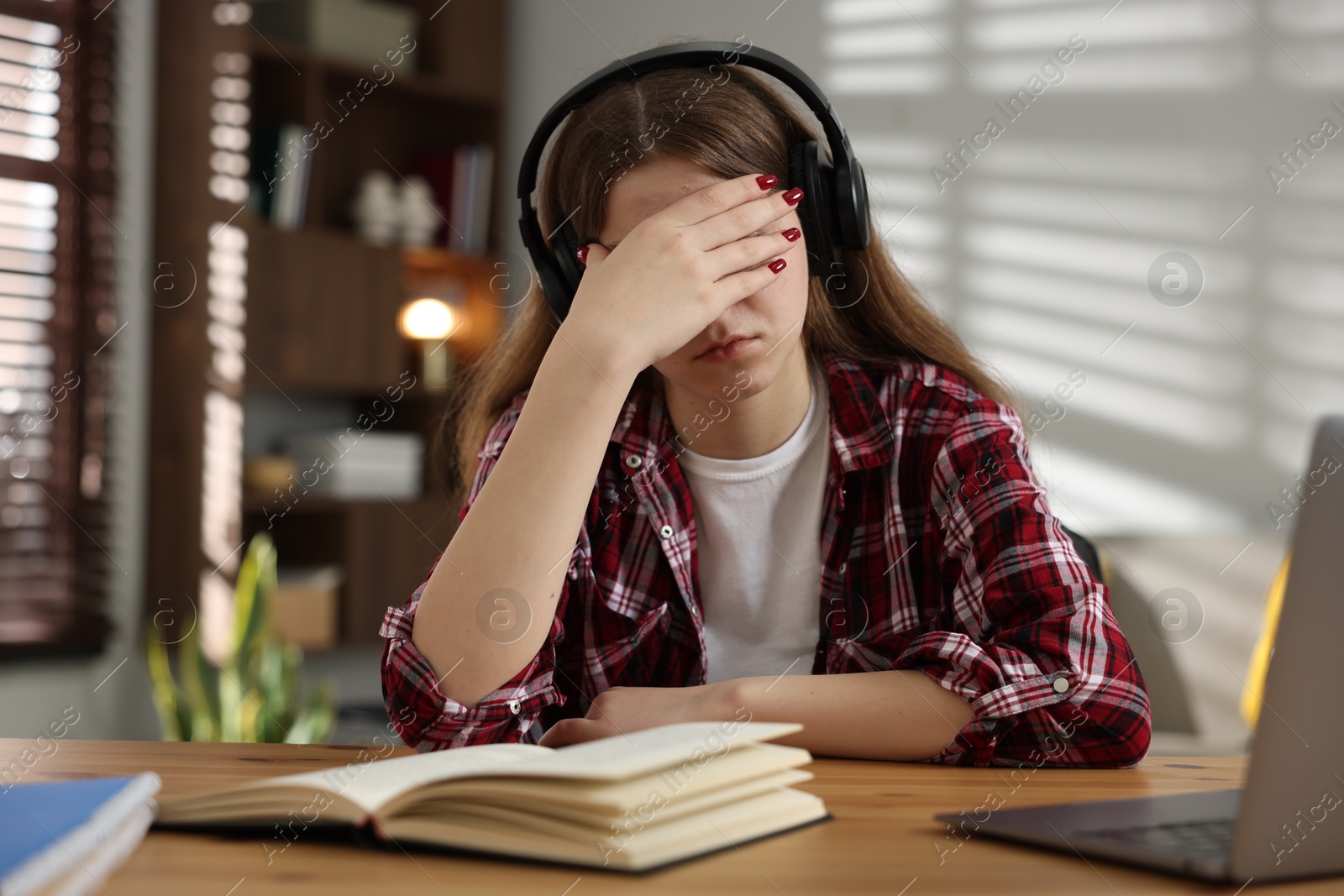 Stressed teenage girl studying at desk indoors Photo of Stressed teenage girl studying at desk indoors