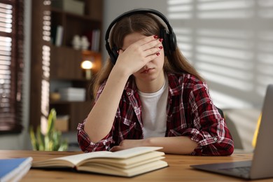 Photo of Stressed teenage girl studying at desk indoors