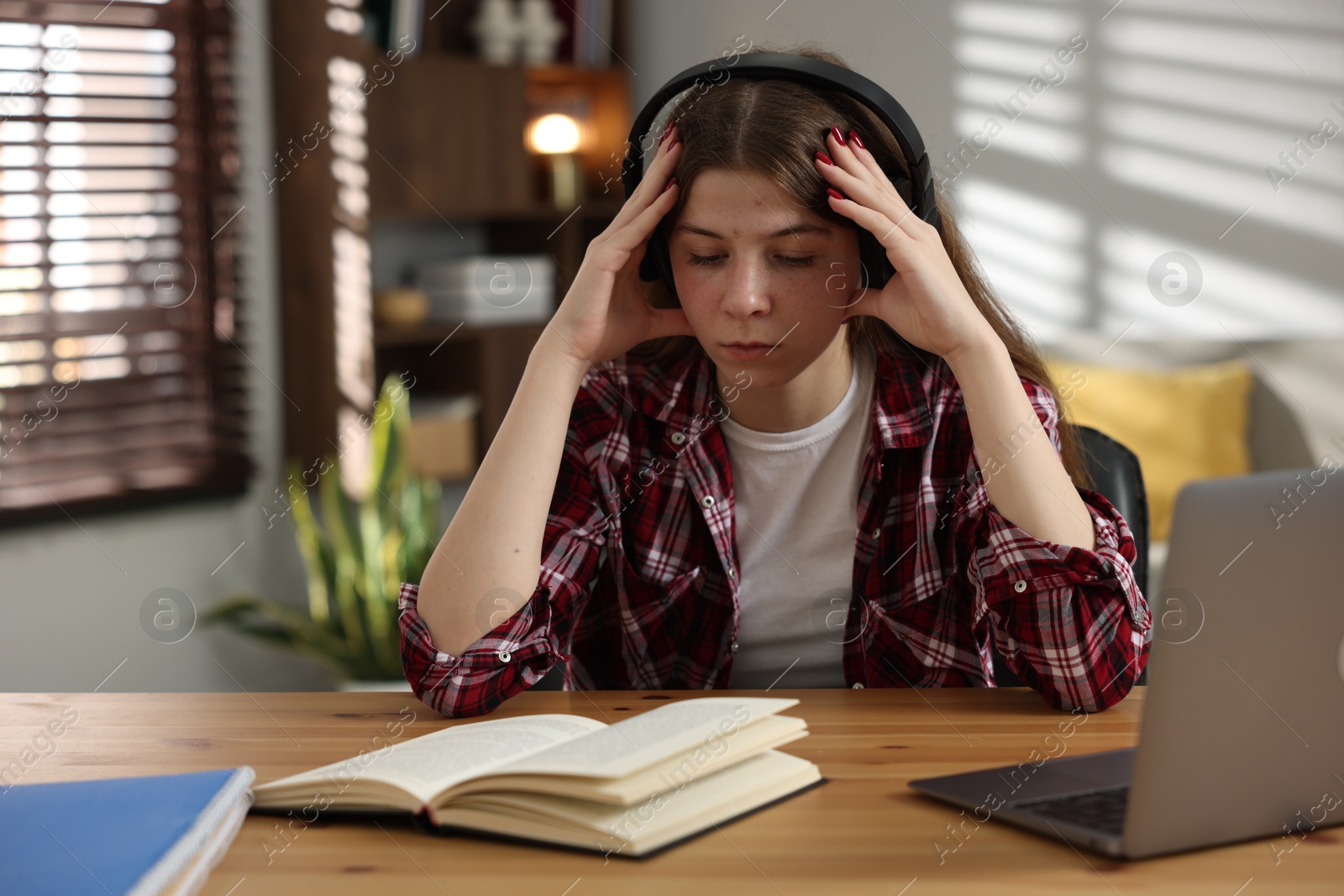 Stressed teenage girl studying at desk indoors Photo of Stressed teenage girl studying at desk indoors