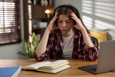 Photo of Stressed teenage girl studying at desk indoors