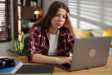 Photo of Stressed teenage girl studying at desk indoors