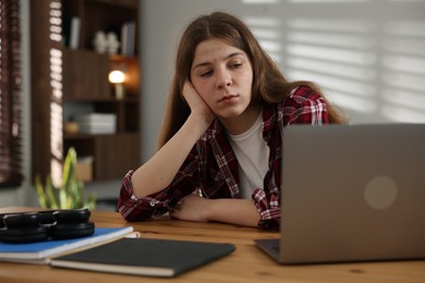 Photo of Stressed teenage girl studying at desk indoors