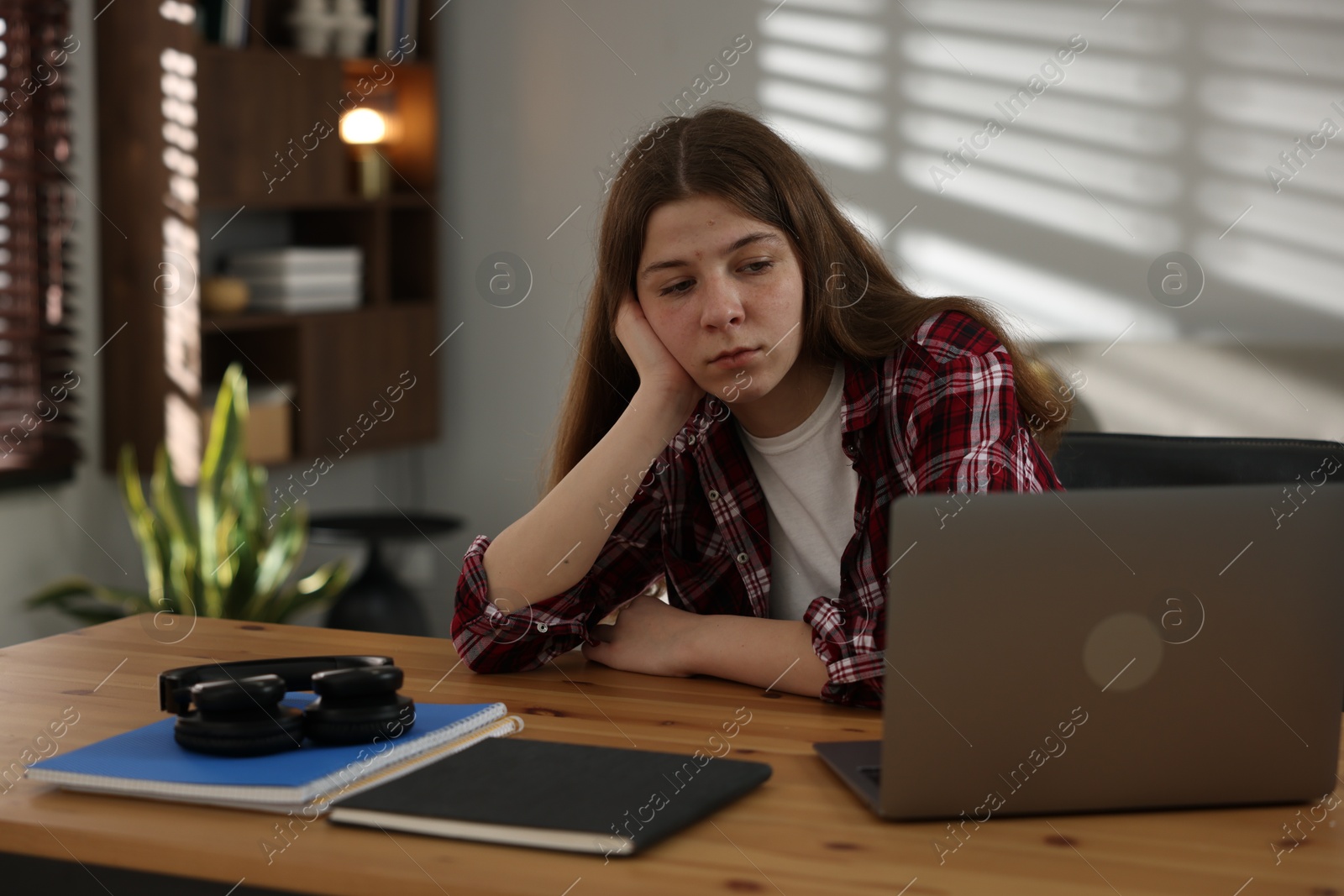 Stressed teenage girl studying at desk indoors Photo of Stressed teenage girl studying at desk indoors