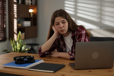 Photo of Stressed teenage girl studying at desk indoors