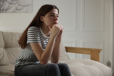 Photo of Depressed teenage girl on sofa at home. Space for text