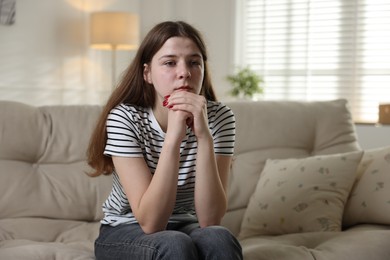 Photo of Depressed teenage girl on sofa at home