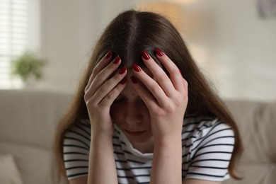 Photo of Depressed teenage girl on sofa at home