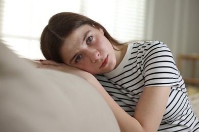 Photo of Depressed teenage girl on sofa at home