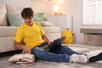 Photo of Teenage student using laptop while studying on floor at home