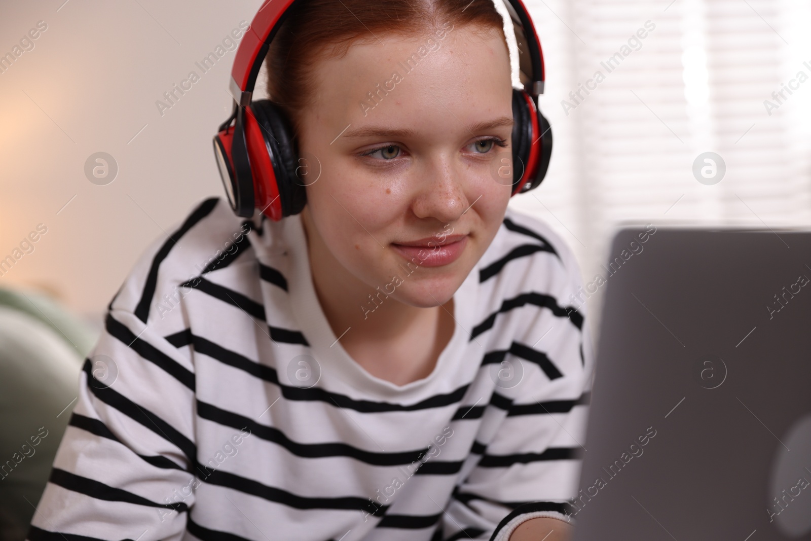 Teenage student in headphones using laptop while studying at home Photo of Teenage student in headphones using laptop while studying at home