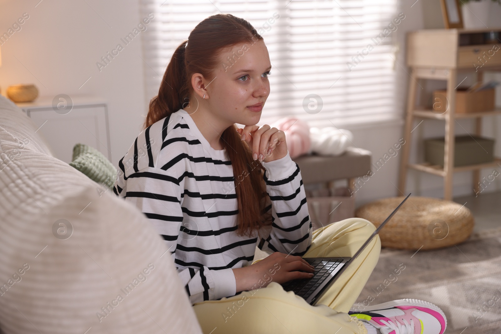 Teenage student using laptop while studying on sofa at home Photo of Teenage student using laptop while studying on sofa at home