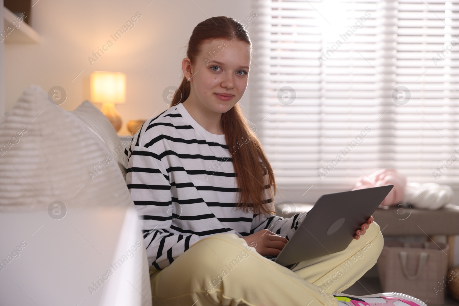 Teenage student using laptop while studying on sofa at home Photo of Teenage student using laptop while studying on sofa at home