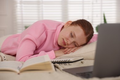 Photo of Tired teenage student sleeping near books and laptop on bed at home