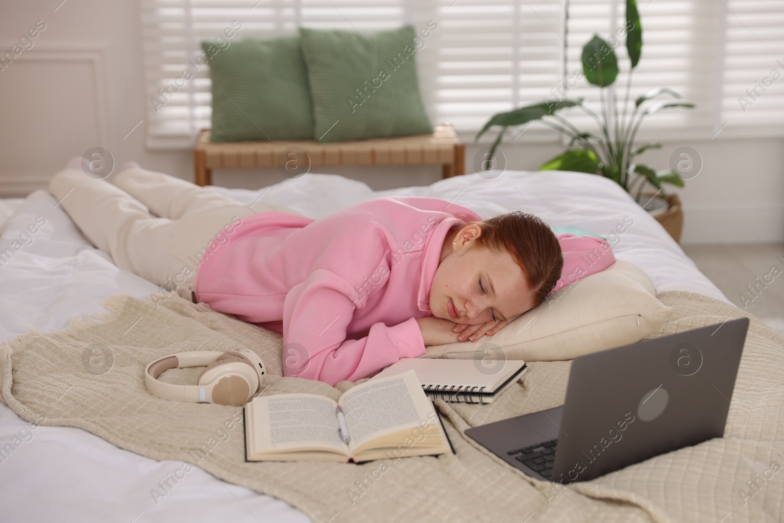 Tired teenage student sleeping near books and laptop on bed at home Photo of Tired teenage student sleeping near books and laptop on bed at home