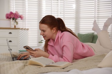 Photo of Teenage student using smartphone while studying on bed at home