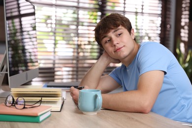 Photo of Teenage student taking notes while studying at table indoors