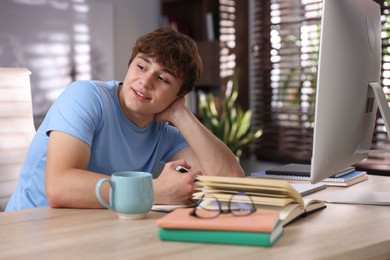 Photo of Teenage student taking notes while studying at table indoors