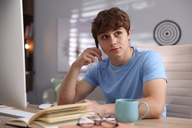 Photo of Teenage student with pen studying at table indoors