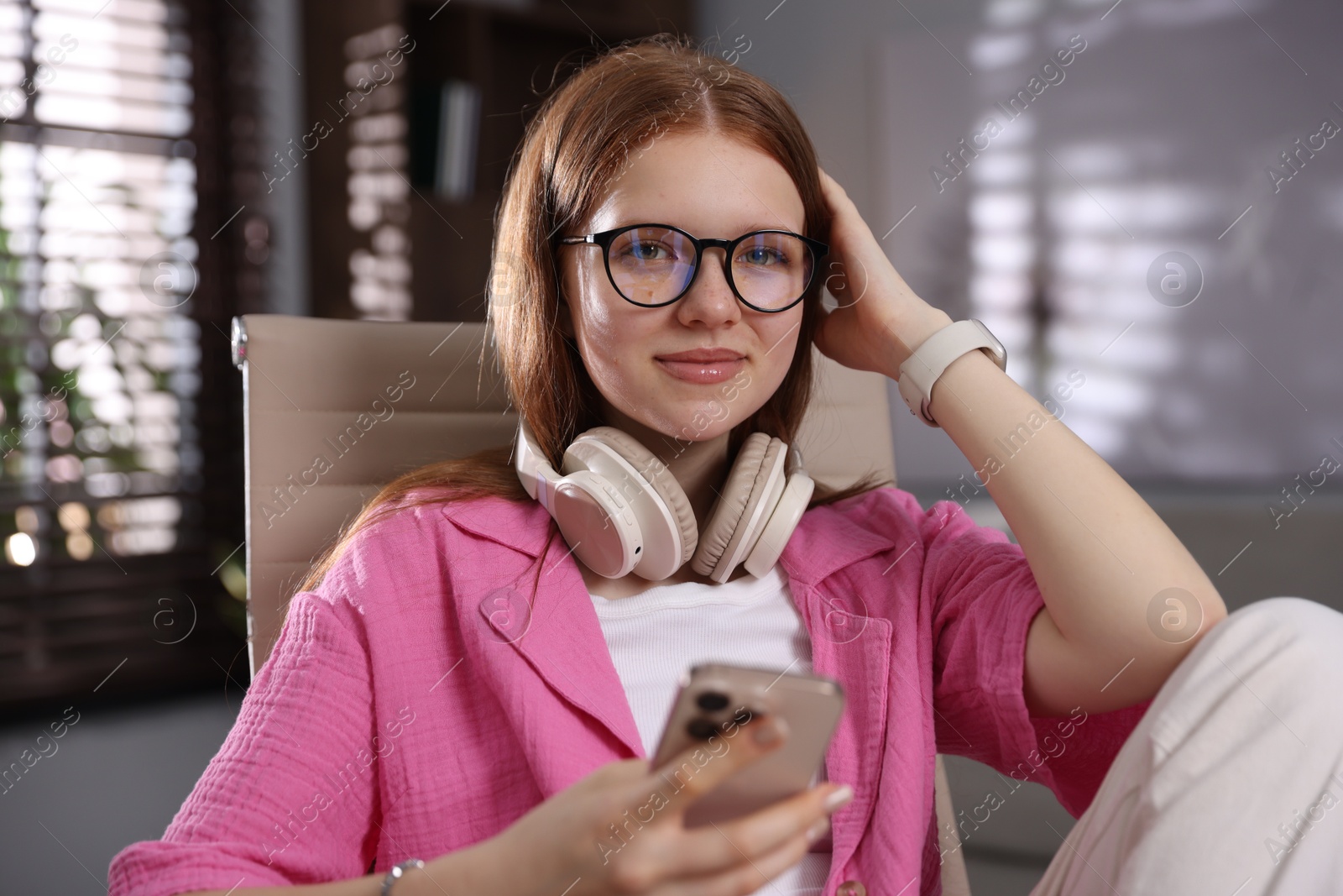 Teenage student with headphones using smartphone while studying at home Photo of Teenage student with headphones using smartphone while studying at home
