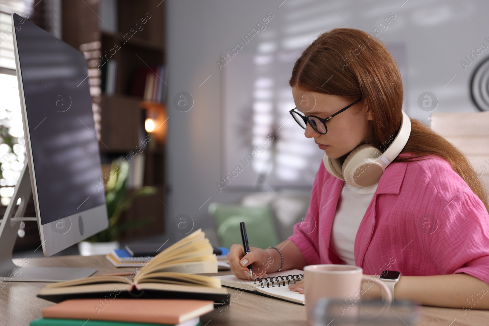 Teenage student taking notes while studying at table indoors Photo of Teenage student taking notes while studying at table indoors