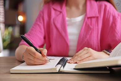Photo of Teenage student taking notes while studying at table indoors, closeup