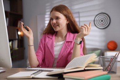 Photo of Teenage student using computer while studying at table indoors