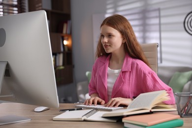 Photo of Teenage student using computer while studying at table indoors